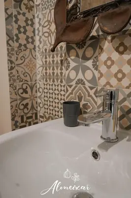 a bathroom sink with a cup on top of it at Guest House Almeixar in Almancil