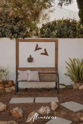 a bench in a garden with birds on a wall at Guest House Almeixar in Almancil