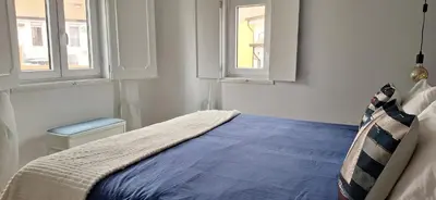 a bedroom with a blue bed with two windows at Irene's Place Marina in Quarteira