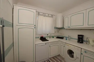 a kitchen with white cabinets and a washing machine at Irene's Place Marina in Quarteira