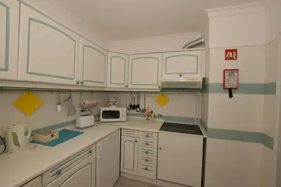 a small kitchen with white cabinets and a microwave at Irene's Place Marina in Quarteira