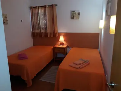 two beds in a room with orange sheets at CASA MALINDI in Albufeira