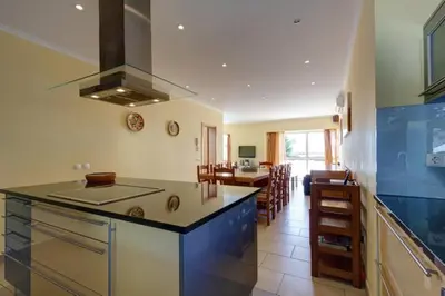 a kitchen with a counter top and a living room at CASA MALINDI in Albufeira