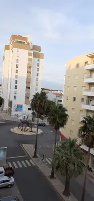 a street with palm trees in front of buildings at Casa dos Teixeiras in Quarteira
