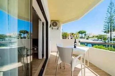 a dining room with a white table and chairs on a balcony at Vilamoura new style apt piscina wifi in Vilamoura