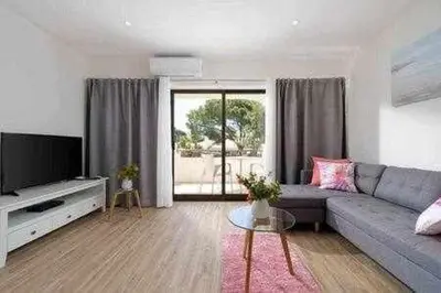 a living room with a couch and a tv at Vilamoura new style apt piscina wifi in Vilamoura