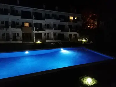 a swimming pool in front of a building at night at Vilamoura T1 com piscina - Mouramar I in Vilamoura