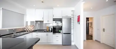 a kitchen with white cabinets and a stainless steel refrigerator at Apartamentos Mónaco by Garvetur in Albufeira