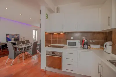 a kitchen with white cabinets and a dining room with a table at Duplex Marina de Vilamoura in Vilamoura