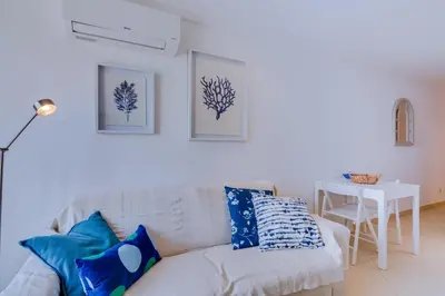 a white couch with blue pillows in a living room at Casa Luz - Quarteira in Quarteira