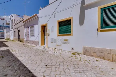 a cobblestone street next to a white building at Casa Luz - Quarteira in Quarteira
