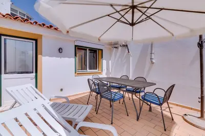 a patio with a table and chairs and an umbrella at Casa Luz - Quarteira in Quarteira