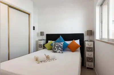 a bedroom with a large white bed with colorful pillows at Moura Suites III - Relaxing view - Vilamoura HD Properties in Vilamoura