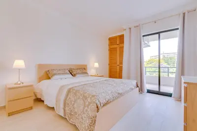 a white bedroom with a bed and a large window at Tália I - City Center - Vilamoura in Vilamoura