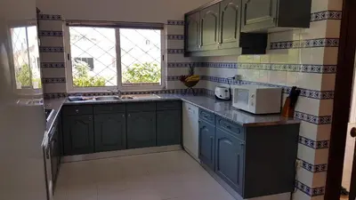 a small kitchen with blue cabinets and a window at Villa Navita in Loulé