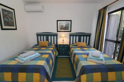 two twin beds in a room with a window at Apt T2 Praia São Rafael Hibiscus 18A - Albufeira, Algarve in Albufeira