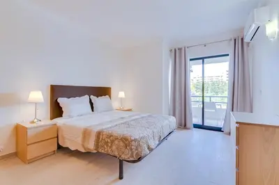 a white bedroom with a bed and a balcony at Tália II - City Center - Vilamoura in Vilamoura
