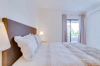 a bedroom with a bed with white pillows and a window at Tália II - City Center - Vilamoura in Vilamoura
