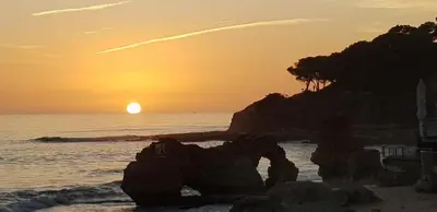 a sunset on the beach with a rock formation at Boas-Vindas in Albufeira