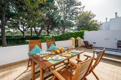 a wooden table and chairs on a patio at Falésia Beach Villa by The Portuguese Butler in Olhos de Água