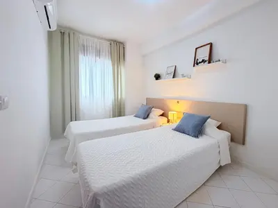 a white bedroom with a bed with blue pillows at Albufeira Center Old Town, 8ppl, 5min Fishermans beach in Albufeira