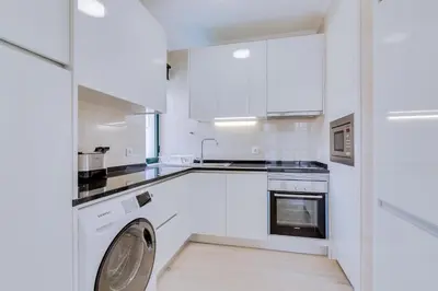 a kitchen with white cabinets and a washer and dryer at Tália IV - City Center - Vilamoura in Vilamoura