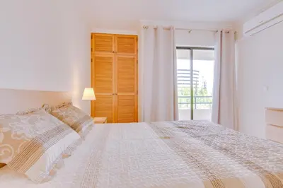 a white bedroom with a bed and a window at Tália IV - City Center - Vilamoura in Vilamoura