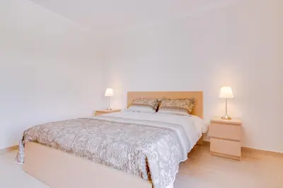 a white bedroom with a large bed with two lamps at Tália IV - City Center - Vilamoura in Vilamoura