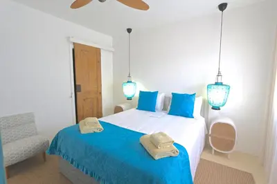 a bedroom with a bed with blue pillows and a chair at Villa Azul - Clever Details, Luxury villa, private pool, access to a club with tennis court, playground, communal pools in Vilamoura