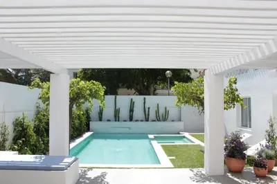 a white pergola over a swimming pool in a backyard at Algarve Beach House with Heated Pool and Jacuzzi in Albufeira