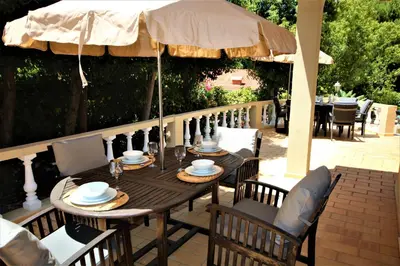 a wooden table and chairs under an umbrella on a patio at Casa Roma in Almancil