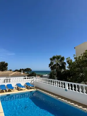 a swimming pool with chairs and the ocean in the background at Vila Mar Central in Albufeira