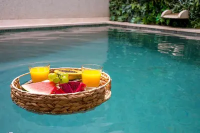a basket of fruit and two glasses of orange juice in a swimming pool at Downtown Pool House in Faro