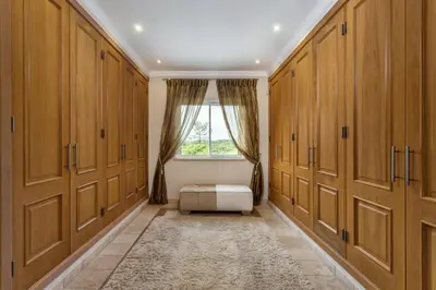 a dressing room with wooden cabinets and a window at Villa Maureena - Quinta do Mar in Almancil