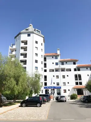 a large white building with cars parked in a parking lot at Vilamoura Marina Apartment with swimming pool in Vilamoura