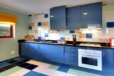 a kitchen with blue cabinets and a checkered floor at Vila Marina -BBQ, pool & garden- by Seareen in Albufeira
