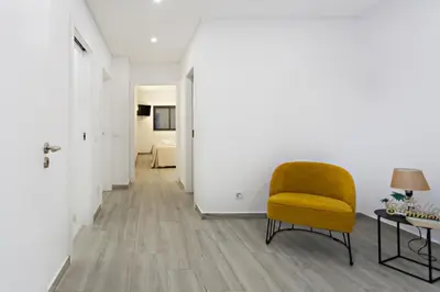 a living room with a yellow chair and a table at Faro Clara Suites in Faro