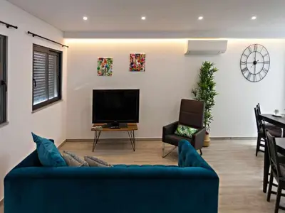 a living room with a blue couch and a television at Faro Clara Suites in Faro