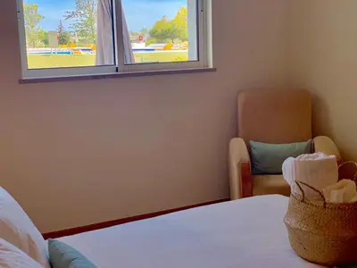 a room with a bed and a window and a chair at Charming Apartment with Private Garden & Pool in Vilamoura