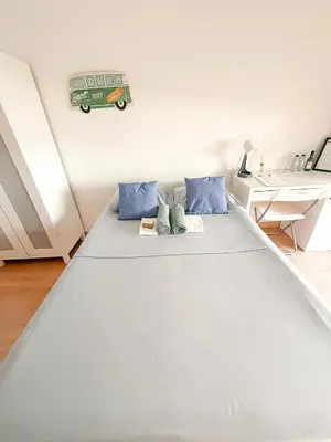 a large white bed in a room with a desk at Surf Vibe Guest House in Faro