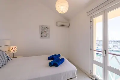 a white bedroom with a bed and a large window at LovelyStay - Two Bedroom Duplex at Vilamoura Marina in Vilamoura