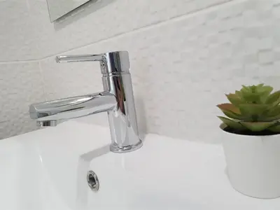 a bathroom sink with a chrome faucet and a plant at Lote 1 Aconchegante in Quarteira