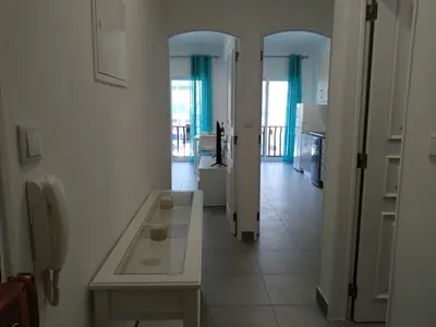 a white room with a table and a kitchen at Lote 1 Aconchegante in Quarteira
