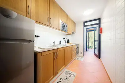 a kitchen with wooden cabinets and a refrigerator at AL - Apartamento Vila Sol F5 AH in Quarteira