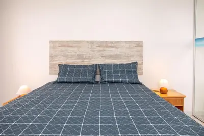 a bedroom with a bed with a blue comforter at O Apartamento A Ramos Palmeira Galé Está inserido num Condomínio com PISCINA, Fica apenas a 250 Metros da Praia da Galé - Apartamento com Ar Condicionado na Sala, Smart TV com Prime Vídeo e Cozinha Completa in Albufeira