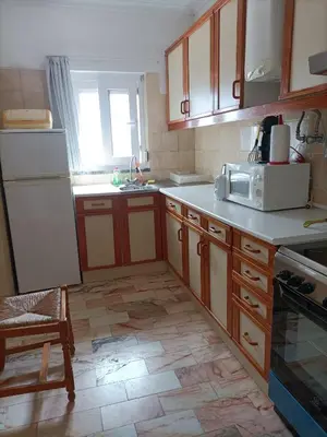 a kitchen with wooden cabinets and a white refrigerator at Oura Li in Albufeira