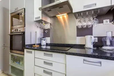 a kitchen with white cabinets and a black counter top at Cozy apartment in Albufeira 76 m² with lovely terrace in Albufeira