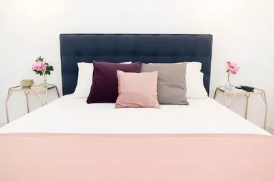 a large bed with white sheets and purple pillows at Casa Olga Vieira in Albufeira
