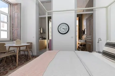 a bedroom with a large bed and a clock on the wall at aleixomor'Aqui in Loulé