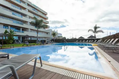 a large swimming pool with chairs and a building at Walkable Marina Vilamoura Aquamar 513 VilamouraSun in Quarteira